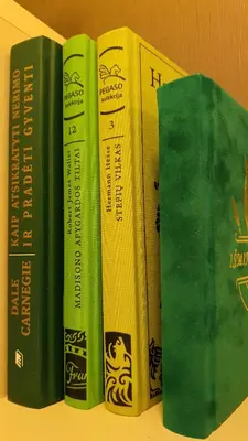 four books sitting next to each other on a shelf at VIP Green House of Hope for 2 in Leliūnai