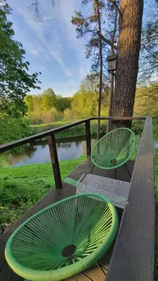 two green chairs sitting on a wooden bench next to a lake at VIP Green House of Hope for 2 in Leliūnai