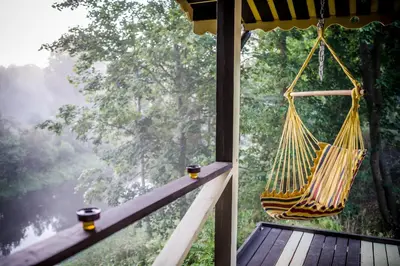 a hammock on a porch with a view of a forest at VIP Yellow dream house Sodyba Geras geltona žalia raudona violetinė in Anykščiai