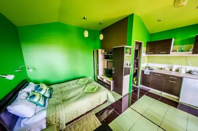 a green room with a bed and a kitchen at VIP Yellow dream house Sodyba Geras geltona žalia raudona violetinė in Anykščiai
