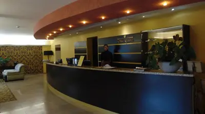 a man standing at a counter in a hotel lobby at Villa Alicante & SPA in Zujūnai