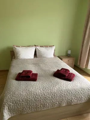 a white bed with two red towels on it at Jaukus butas in Anykščiai