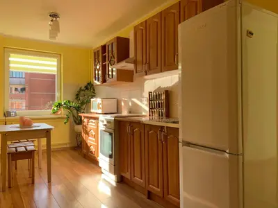 a kitchen with wooden cabinets and a white refrigerator at Jaukus butas in Anykščiai