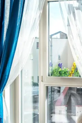 a window with blue curtains and a flower pot at HaPPy INN Studio Historic center, Self check-in, AC, Parking in the undergrnd Garage, in Vilnius