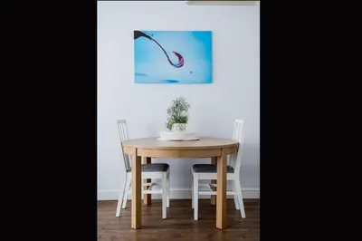 a dining room table and chairs with a painting on the wall at Vilnius street apartment in Vilnius