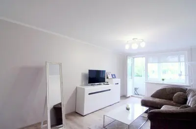 a living room with a couch and a tv and a mirror at Apartamentai Domeva in Druskininkai