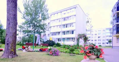 a large white building with flowers in a park at Apartamentai Domeva in Druskininkai
