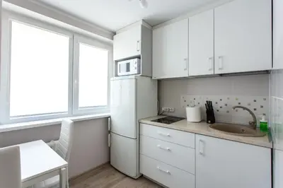 a white kitchen with a sink and a refrigerator at Apartamentai Domeva in Druskininkai