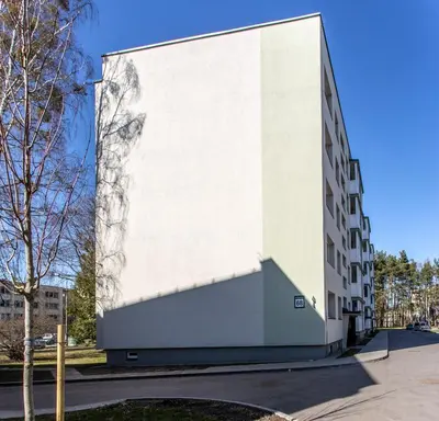 a white building with a shadow on the side of it at Apartamentai Domeva in Druskininkai