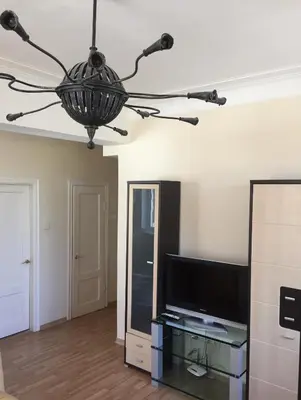 a living room with a television and a chandelier at Old Town apartament in Šiauliai