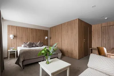 a hotel room with a bed and a vase of flowers on a table at Big Stone in Ukmergė
