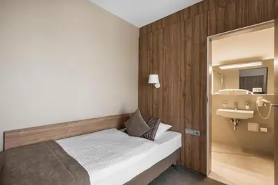 a small bedroom with a bed and a sink at Big Stone in Ukmergė