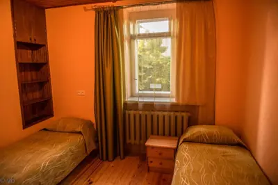 a bedroom with two twin beds and a window at Prie upes in Kunioniai
