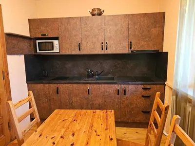 a kitchen with a wooden table and a microwave at Prie upes in Kunioniai