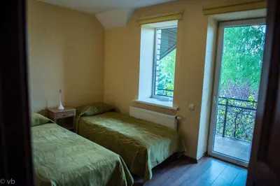 two beds in a room with two windows at Prie upes in Kunioniai