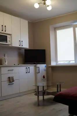 a kitchen with white cabinets and a table and a window at Anyksciu liuksas in Anykščiai