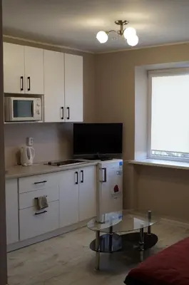 a kitchen with white cabinets and a table and a window at Anyksciu liuksas in Anykščiai