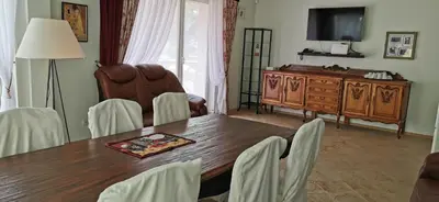 a dining room with a table and chairs and a television at Green Gile Villa in Druskininkai Center in Druskininkai