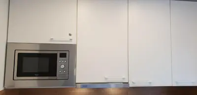 a microwave oven in a kitchen with white cabinets at City apartment Anykščiai in Anykščiai