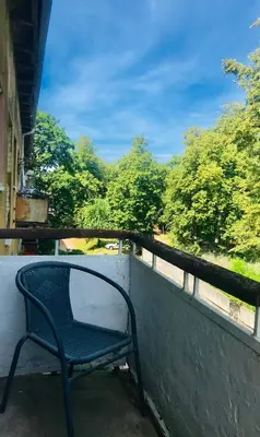 a chair sitting on a balcony looking out at trees at City break. Center in Kaunas