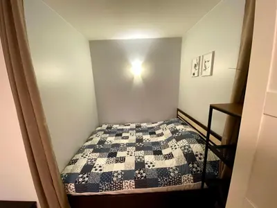 a small bedroom with a bed with a blue and white quilt at Your Home - Central studio apartment, balcony, parking & Self Check-in in Vilnius