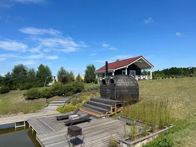 a building with a wooden deck next to a body of water at Villa Vita in Seimėnai