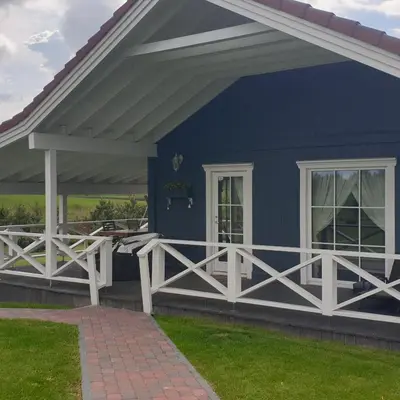 a blue house with a porch and a white railing at Villa Vita in Seimėnai