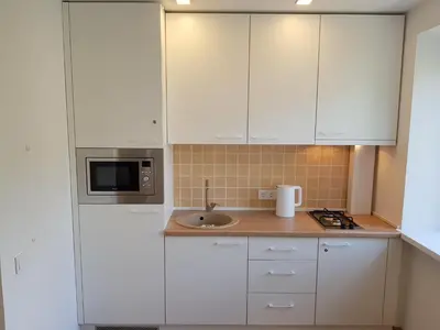 a kitchen with white cabinets and a sink and a microwave at Anykščiai Cozy Studio in Anykščiai