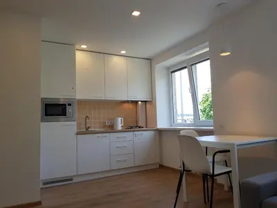 a kitchen with white cabinets and a table with chairs at Anykščiai Cozy Studio in Anykščiai