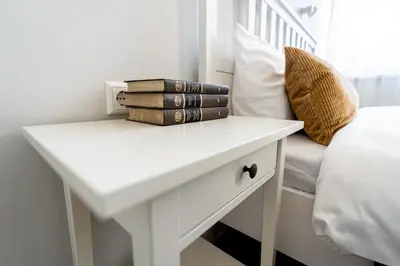 a white table with books on it next to a bed at Beautiful apartment in the heart of Kaunas in Kaunas
