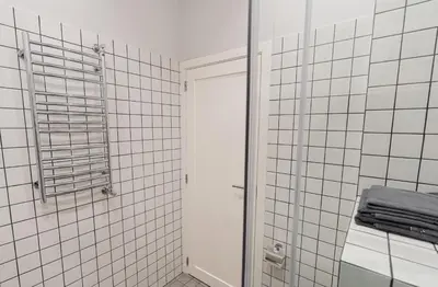 a white tiled bathroom with a shower and a mirror at Beautiful apartment in the heart of Kaunas in Kaunas