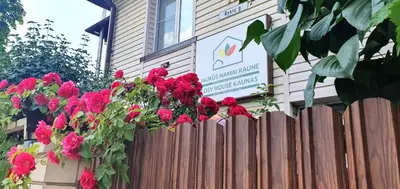 a wooden fence with red flowers in front of a building at ApartHotel SAVAS 3 Studio and parking in Kaunas