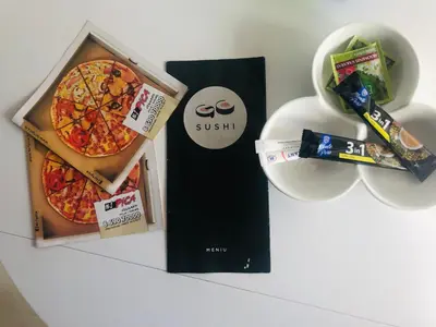 two pizzas in a box and a bowl of food at Romeo VIP apartamentai in Panevėžys