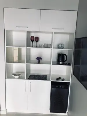 a white book shelf with a laptop and wine glasses at Romeo VIP apartamentai in Panevėžys