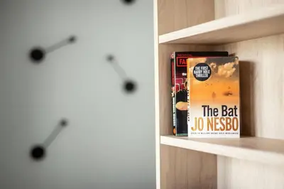 a book shelf with a clock and a book at Brand New Smart House City Center in Vilnius