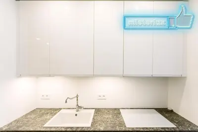 a kitchen with white cabinets and a sink at Mieterlux White in Vilnius