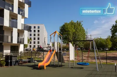 a playground with an orange slide in front of a building at Mieterlux White in Vilnius