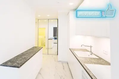 a kitchen with white counters and a blue sign on the wall at Mieterlux White in Vilnius