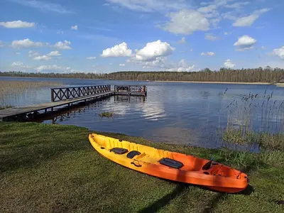 a yellow canoe sitting on the grass next to a dock at Du Horizontai in Molėtai