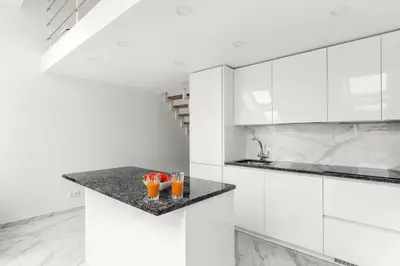 a white kitchen with two drinks on a counter at Luxurious Kaunas Basilica Apartment in Old Town by Urban Rent in Kaunas