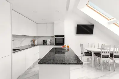 a kitchen with white cabinets and a table with chairs at Luxurious Kaunas Basilica Apartment in Old Town by Urban Rent in Kaunas