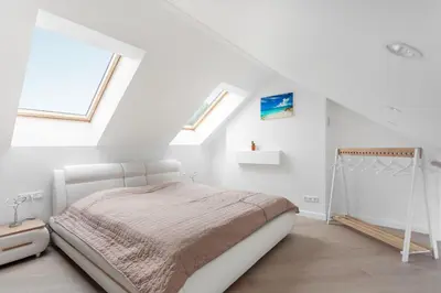 a white bedroom with a bed and two windows at Luxurious Kaunas Basilica Apartment in Old Town by Urban Rent in Kaunas