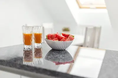 a bowl of watermelon and two glasses of juice on a counter at Luxurious Kaunas Basilica Apartment in Old Town by Urban Rent in Kaunas