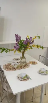 a white table with a vase of purple flowers on it at Kaunas Downtown Apartments in Kaunas
