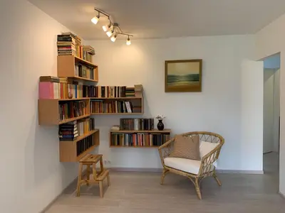 a room with a chair and a book shelf with books at Homely apartment in Kėdainiai in Kėdainiai