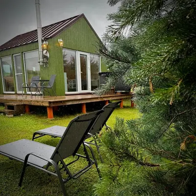 a green house with two chairs and a tree at ALANTOS ŽIRGAI Holiday Villas sauna or hottube additional price in Alanta