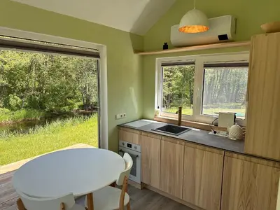 a kitchen with a table and a sink and two windows at ALANTOS ŽIRGAI Holiday Villas sauna or hottube additional price in Alanta