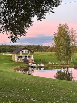 a farm house with a pond in front of it at ALANTOS ŽIRGAI Holiday Villas sauna or hottube additional price in Alanta