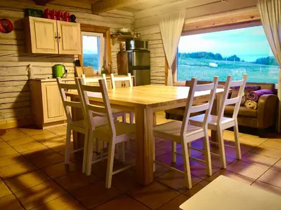 a wooden table and chairs in a kitchen with a window at ALANTOS ŽIRGAI Holiday Villas sauna or hottube additional price in Alanta