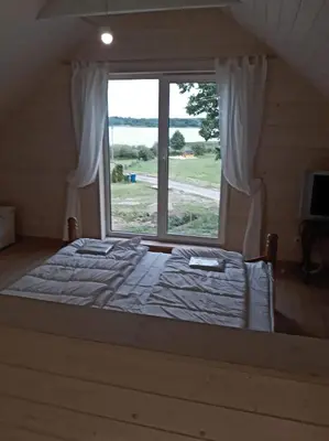 a bed in a room with a large window at Kaimo Vila “Padange” in Kančėnai